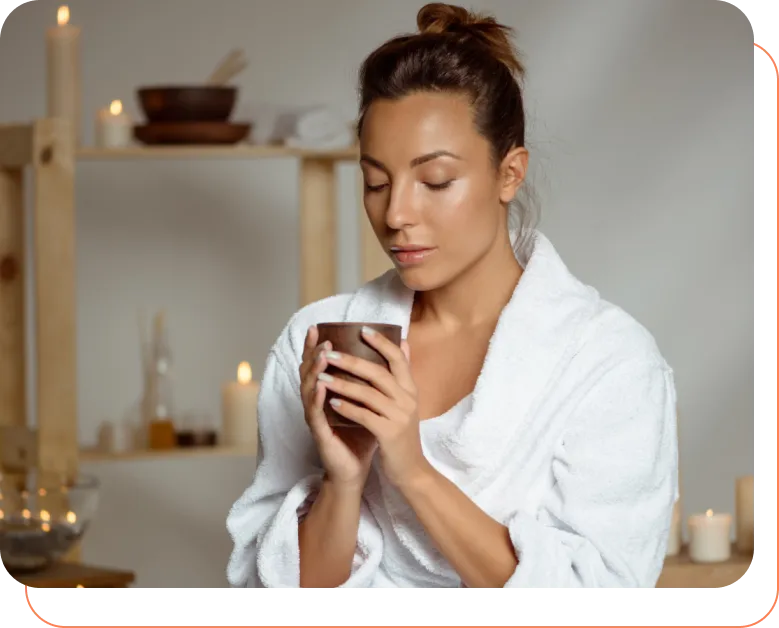 Mulher de roupão segurando uma xícara em ambiente de spa