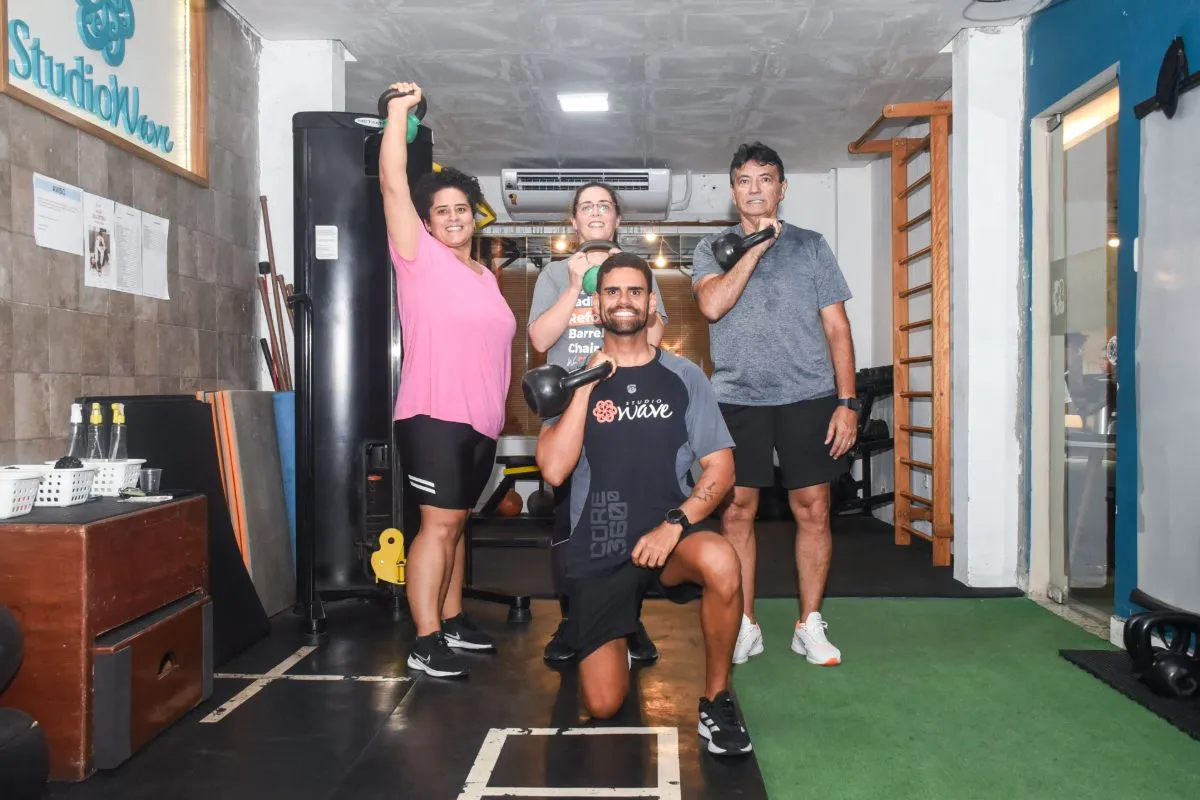 Professor e alunos treinando com kettlebells no studio