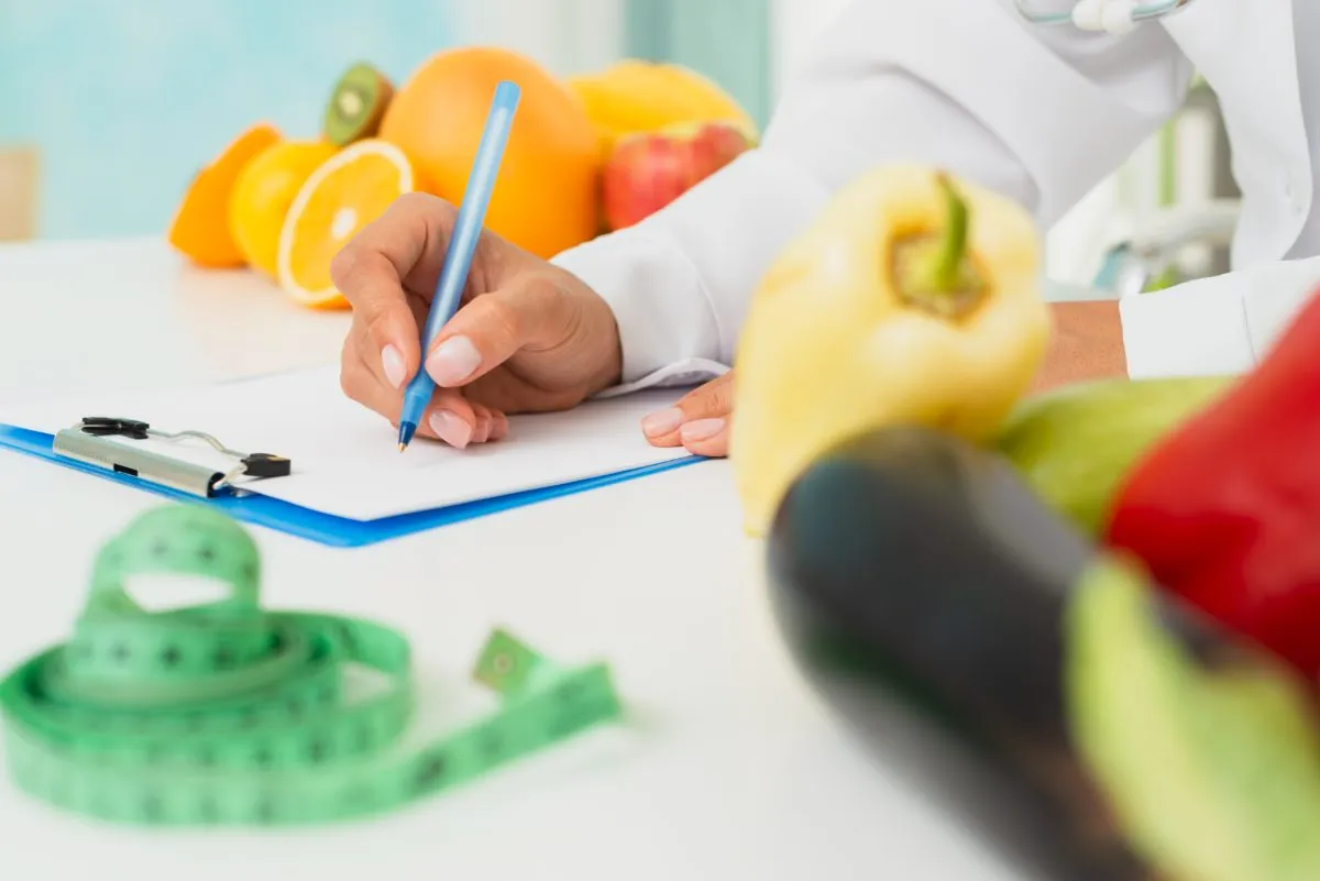 Nutricionista anotando plano ao lado de frutas e legumes