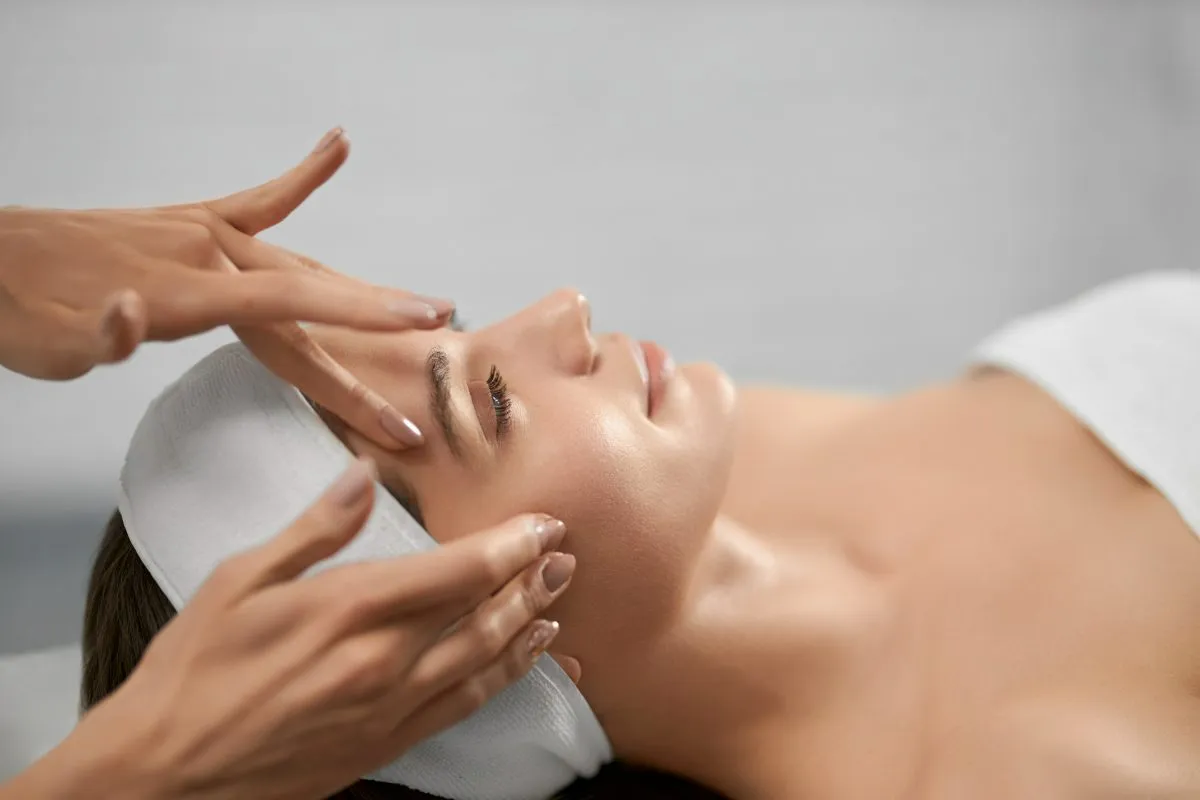 Profissional realizando massagem facial em cliente